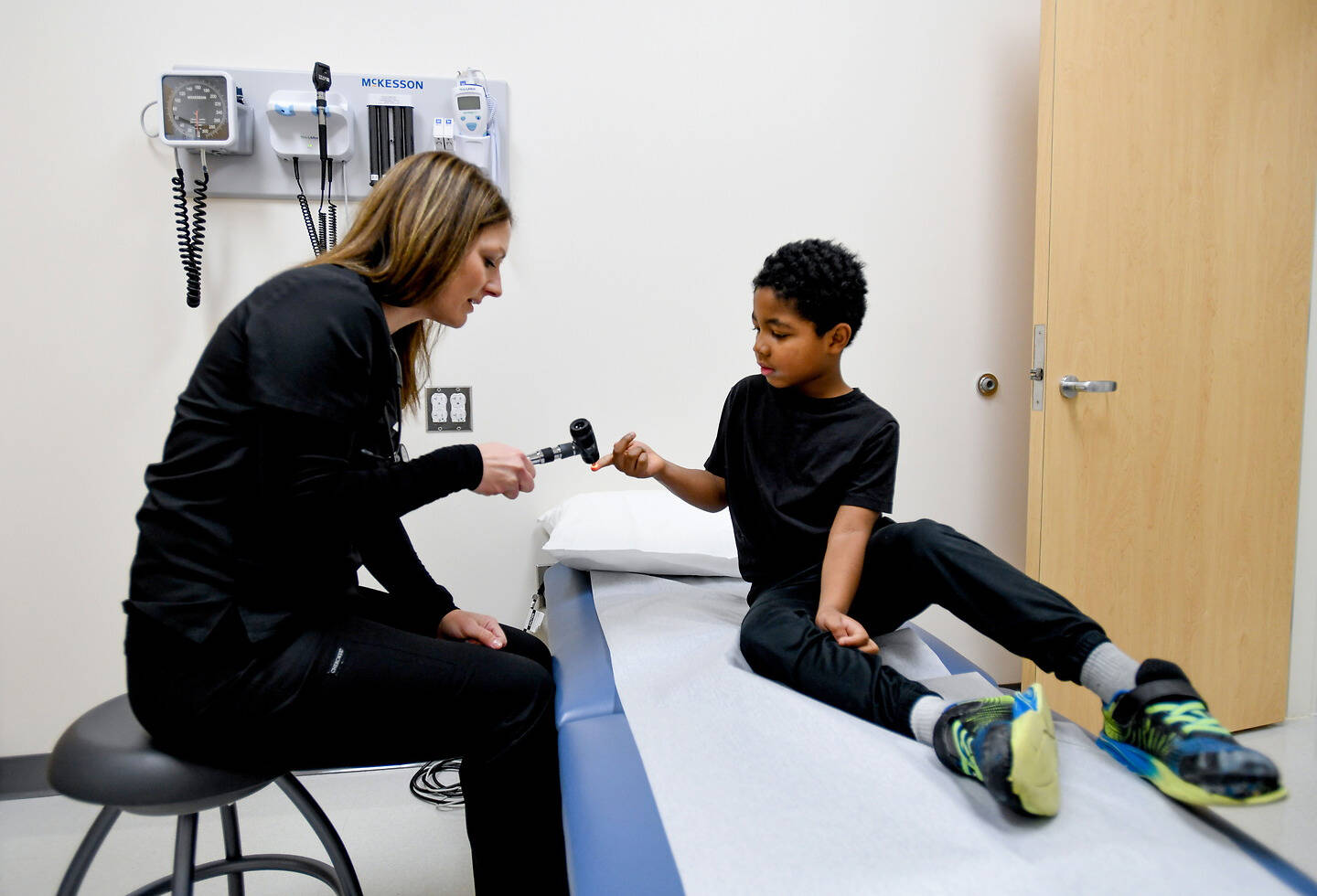 A healthcare professional interacts with a child during a medical examination in a clinical setting.